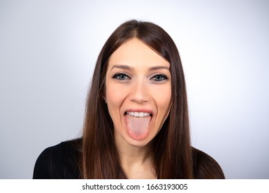 Funny immage of a smiling girl showing tongue. Portrait of a young Caucasian woman with face makeup