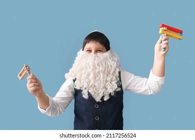 Funny Jewish boy with graggers for Purim holiday and fake beard on grey background