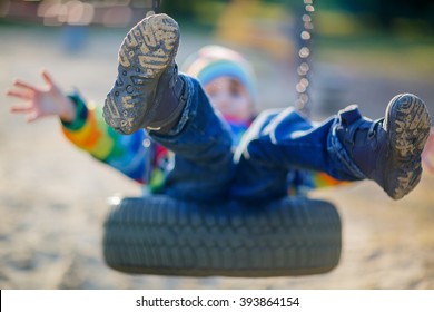 Funny Kid Boy Having Fun With Chain Swing On Outdoor Playground. Child Swinging On Warm Sunny Spring Or Autumn Day. Active Leisure With Kids. Selective Focus