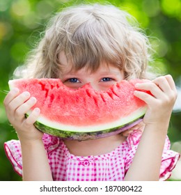 Funny Kid Eating Watermelon Outdoors In Summer Park. Child, Baby, Healthy Food