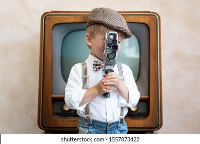 Funny Kid Holding Vintage Camera. Happy Child Having Fun At Home. Retro Cinema Concept