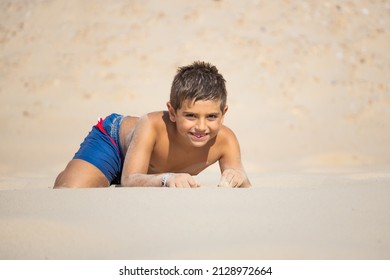 Funny Kid Lying Down On A Sand Of A Beach