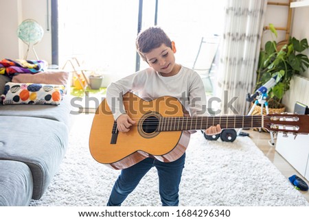 Funny kid playing guitar at home