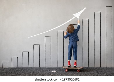 Funny Kid Pretend To Be Businessman. Child Draws Chalk Graph On The Wall. Business Startup And Development Concept