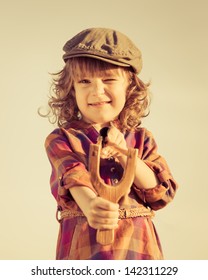 Funny Kid Shooting Wooden Slingshot. Retro Toned Image