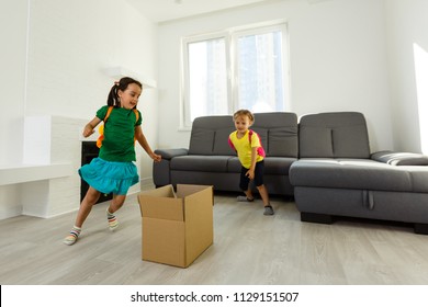 Funny Kids Boy And Girl Running Inside Luxury Big Modern House On Moving Day, Cute Children Entering Exploring New Home