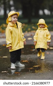 Funny Kids In Rain Boots Playing With A Puddle