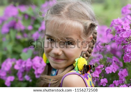 Funny laughing 5-6 years old girl with a butterfly on her hair, happy summertime and childhood, outdoor 
