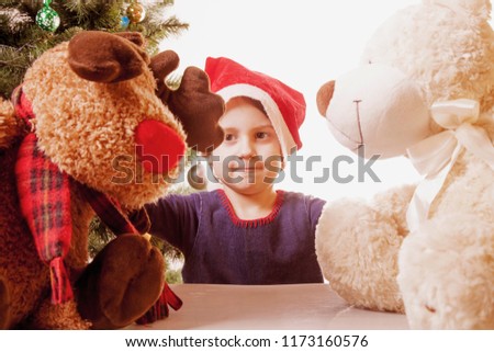 Funny Laughing Christmas child girl with red fluffy Santa Hat (New Year, Christmas, holidays, gifts concept)