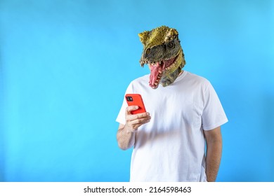 Funny Laughing Dinosaur Head On Human Body On White T-shirt On Blue Background, Looking At His Smart Phone, Clip Art, Negative Space.