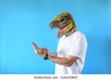 Funny Laughing Dinosaur Head On Human Body On White T-shirt On Blue Background, Looking At His Smart Phone, Looking To The Left. Clip Art, Negative Space.