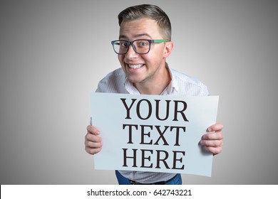 Funny laughing guy (men, student, businessman) of european appearance in casual clothes and glasses is holding a white sheet of paper with text Your text here