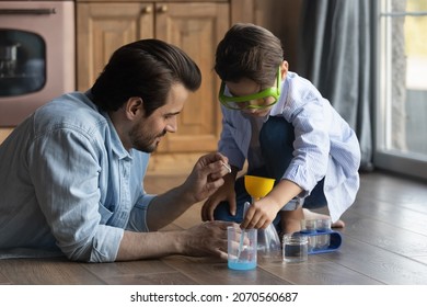 Funny learning. Caring millennial father preteen son do simple chemical experiments using chemistry set for kids. School age boy study experimental science in education game playing on floor with dad - Powered by Shutterstock