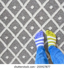 Funny Legs In Mismatched Socks On Gray Carpet.