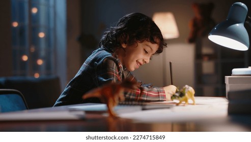 Funny little asian kid drawing at home  Boy and curly hair drawing and pencils paper in the evening  learning art  having fun at home    hobby concept