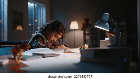Funny little asian kid drawing at home  Boy and curly hair drawing and pencils paper in the evening  learning art  having fun at home    hobby concept 