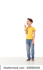 Funny little boy in casual clothes is pointing up, looking away and smiling, isolated on a white background