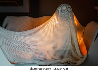 Funny little child playing under the blanket with light and toys inside. Homemade kid tent, cozy home atmosphere. Child imagination. Quarantine and self isolation during pandemic. Social distancing  - Powered by Shutterstock