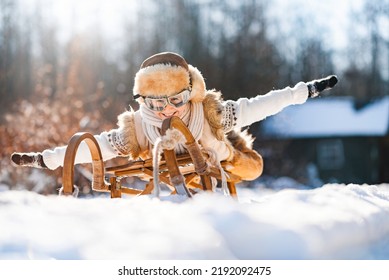 Funny little child runs on sledge in snow. Active sports games in winter time. Happy winter holidays concept.