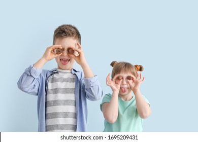 Funny little children with chocolate candies on color background