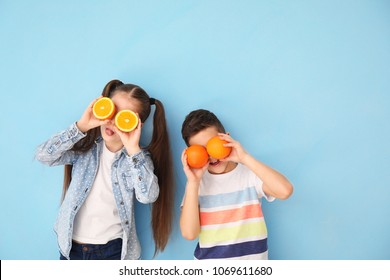 Funny Little Children With Citrus Fruit On Color Background