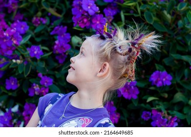 Funny Little Cute Caucasian Girl With Braids For Crazy Hair Day At School On Purple Flowers Tibouchina Outside Nature Background