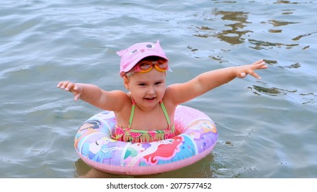 Funny Little Girl 3 Years Old Swims With An Inflatable Ring, A Sun Cap And Swimming Goggles In The Sea. Summer Vacation Concept, Learning To Swim: Antalya, Manavgat Turkey - July 28, 2021.