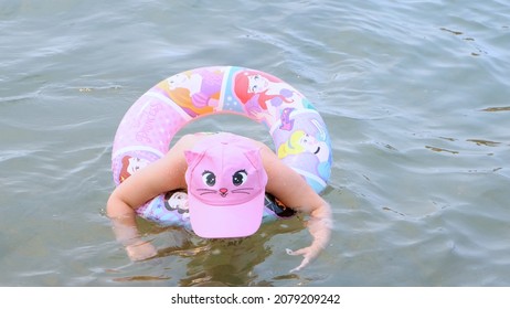 Funny Little Girl 3 Years Old Swims With An Inflatable Ring, A Sun Cap And Swimming Goggles In The Sea. Summer Vacation Concept, Learning To Swim: Antalya, Manavgat Turkey - July 28, 2021.