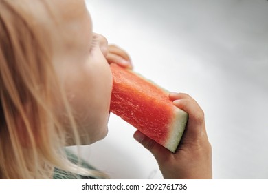 Funny Little Girl Eating Watermelon Close-up. Cute Child With Watermelon Indoors. Concept Of Healthy Food, Summertime. Copy Space