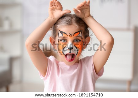 Funny little girl with face painting at home
