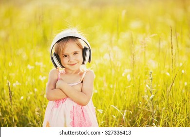 Funny little girl with headphones on nature