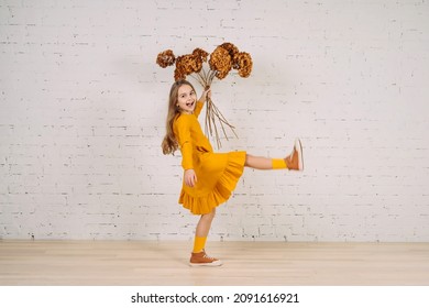 Funny little girl making a big step holding dried flowers hydrangea. Boho style kids dress. Copy space for text.