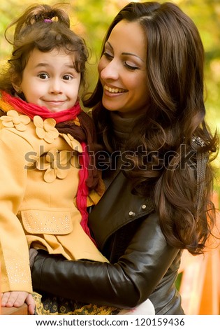 Funny little girl and mother in autumn forest