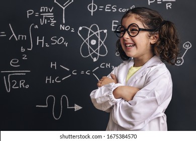 funny little girl science student with glasses in lab coat laugh on school blackboard background with hand drawings science formula pattern, back to school and successful female career concept - Shutterstock ID 1675384570