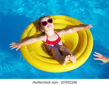 Funny Little Girl Swims In A Pool In An Yellow Life Preserver