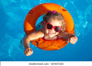 Funny Little Girl Swims In A Pool In An Orange Life Preserver