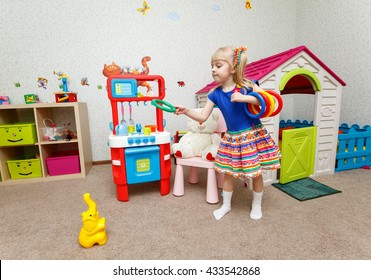 Funny little girl throwing plastic rings on toy elephant
