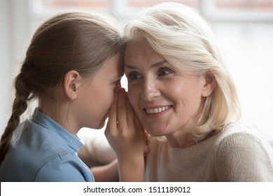 Funny Little Granddaughter Whisper To Curious Grandmother Ear Tell Secret Information Share Hearsay, Small Teen Girl Grandchild Chatting Gossip With Senior 50 Grandparent, Special Bonding Concept