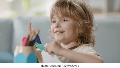 Funny little kid playing while crafting something  Cute boy cutting paper and scissors for children   happily smiling    happy childhood concept 