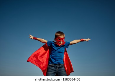 Funny little power super hero child (boy) in a red raincoat. Superhero concept
