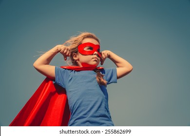 Funny little power super hero child (girl) in a red raincoat. Superhero concept. Instagram colors toning