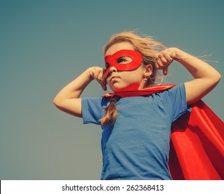Funny little power super hero child (girl) in a red raincoat. Superhero concept. Instagram colors toning