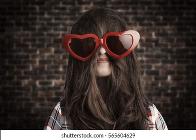 funny love concept of a woman, wearing extra large heart shaped glasses above the hair that covers her face 