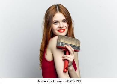 Funny lovely woman with brush for paint repairs, light background