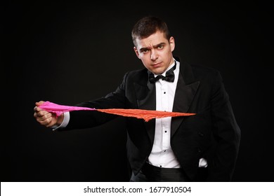 Funny Magic Man In Tuxedo And Bow Tie With Colorful Handkerchief Isolated On Black Background