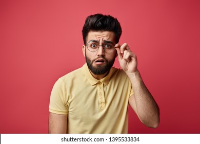 funny man with bad eyesight trying to see written on poster, board.expresses surprise , close up photo. isolated pink background.man in yellow T-shirt touching his eyeglasses and looking at camera - Powered by Shutterstock