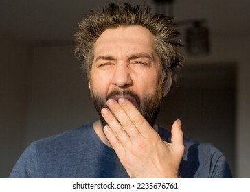 Funny man with a beard after waking up yawns, looking at the morning sun. Close up portrait. - Powered by Shutterstock