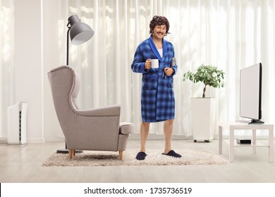 Funny Man In A Blue Bathrobe Holding A Cup At Home In A Living Room