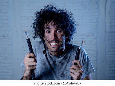 Funny man with burns and smoke holding electrical cable after getting a electric shock at home. Sad husband with dirty burnt face guilty expression. Domestic accidents, DYI and Electricity danger.