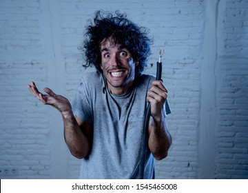 Funny Man With Burns And Smoke Holding Electrical Cable After Getting A Electric Shock At Home. Sad Husband With Dirty Burnt Face Guilty Expression. Domestic Accidents, DYI And Electricity Danger.